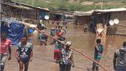 Menschen in überflutetem Dorf. Für Überschwemmungen in Afrika spenden.