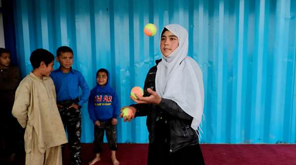Mädchen jongliert vor anderen Kindern im mobilen Circus im Darul-Aman Camp.