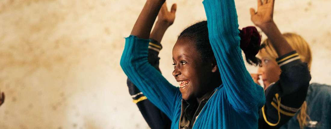 Schülerin in Sodo in Äthiopien strahlt und hebt die Hände