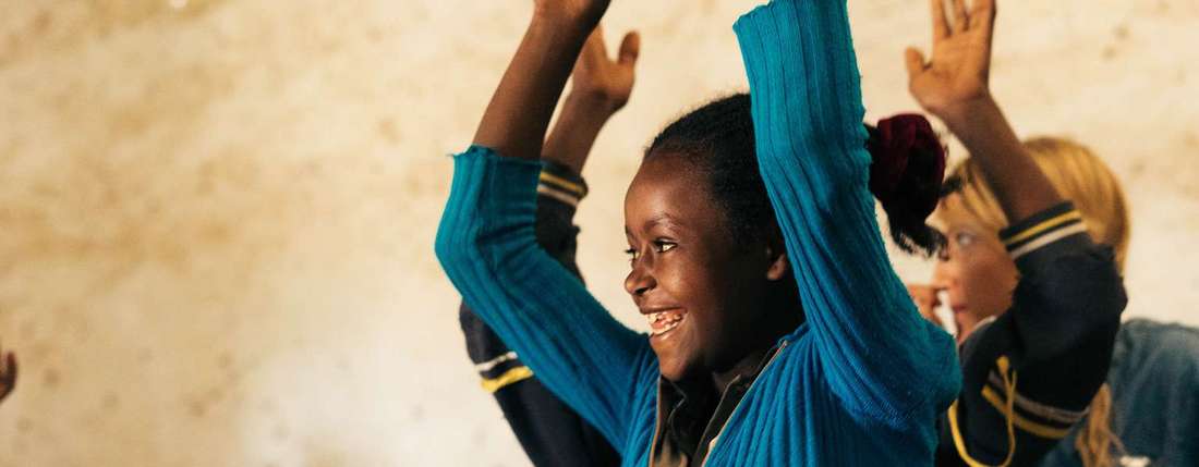 Schülerin in Sodo in Äthiopien strahlt und hebt die Hände
