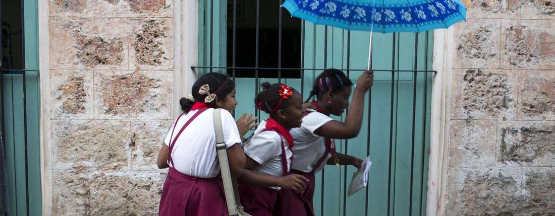 drei Mädchen auf dem Weg zu Schule mit Regenschirm