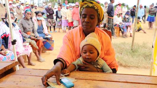 Eine Frau und ihr Baby beim Cash Transfer in Madagaskar. Anticipatory Action bedeutet auch, von Notlagen gefährdete Menschen zu ermöglichen, für sich selbst sorgen zu können.