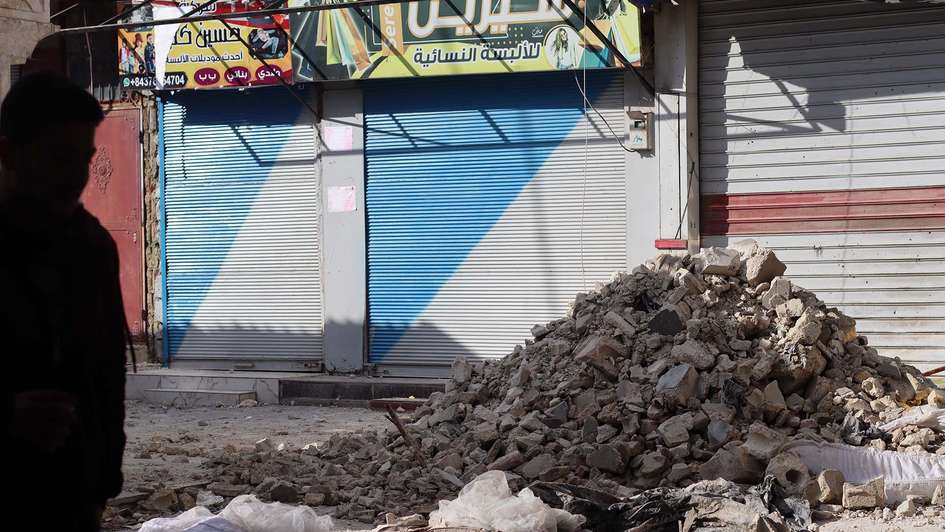 Ein Trümmerhaufen vor geschlossenen Ladentoren in einer Stadt.
