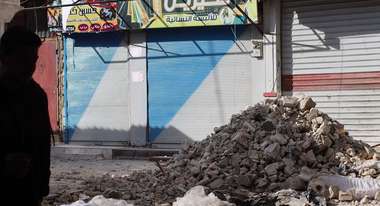 Ein Trümmerhaufen vor geschlossenen Ladentoren in einer Stadt.