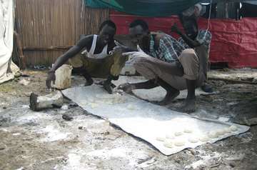 Männer kneten Brotteig aus der Not heraus auf Matten.