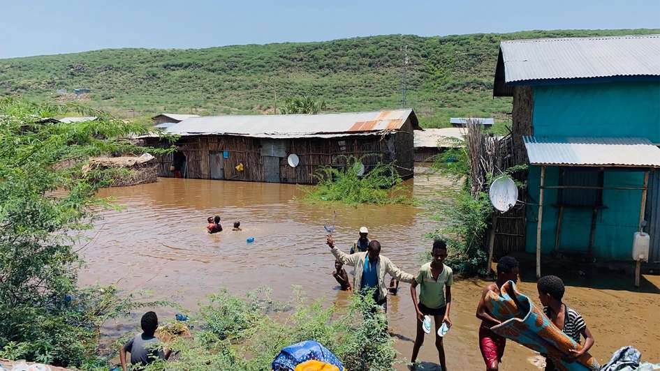 Überschwemmungen in Ostafrika: Überschwemmte Häuser und Menschen, die in Wasser waten.