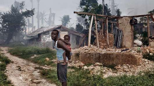 Ein Mann mit seiner Tochter vor den Ruinen eines Hauses in Grand Anse.