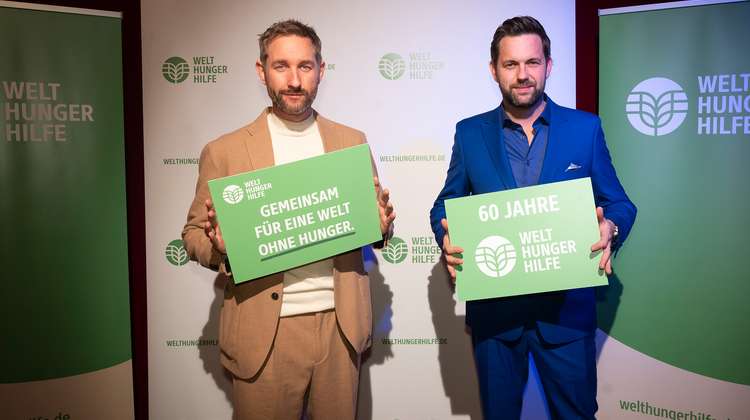 Daniel Boschmann und Matthias Killing halten Schild der Welthungerhilfe in die Kamera.