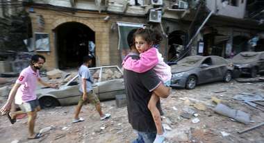 Ein Mann trägt nach einer Explosion ein Kind auf dem Arm, Beirut.