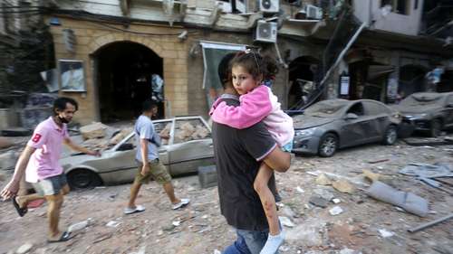 Ein Mann trägt nach einer Explosion ein Kind auf dem Arm, Beirut.