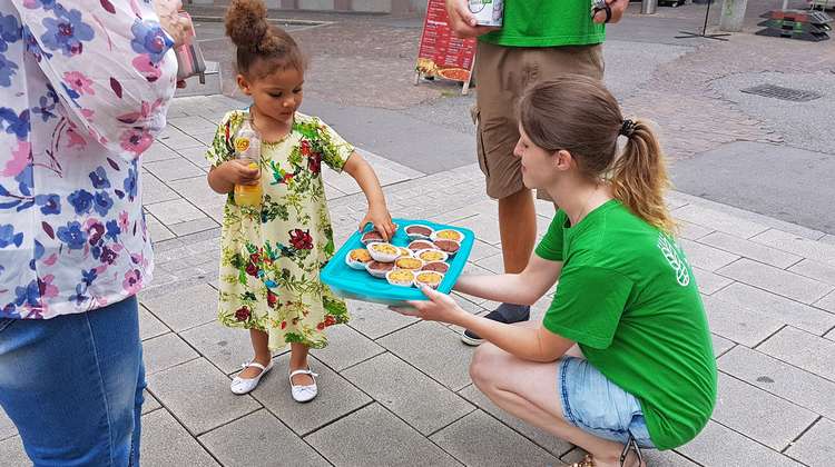 Ein kleines Mädchen nimmt sich einen Muffin vom Tablett.