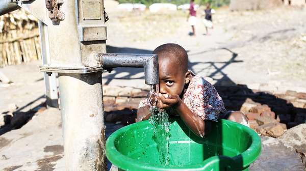 Junge trinkt frisches Wasser aus dem Hahn