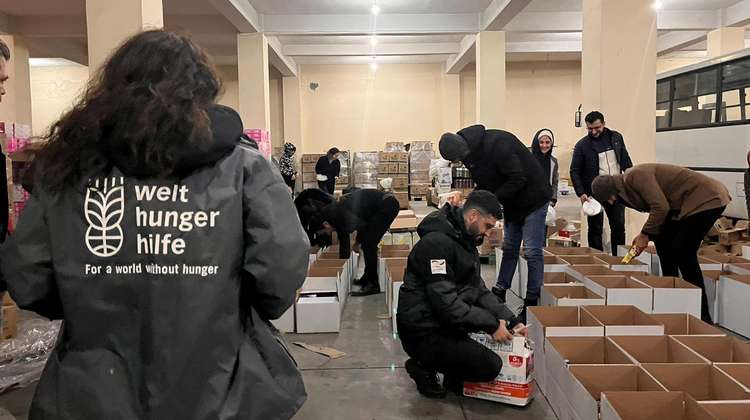 Mehrere Menschen in Welthungerhilfe-Jacken packen Kartons.
