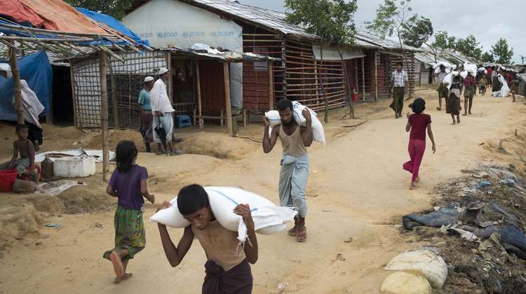 Geflüchtete Rohingya tragen Säcke von einer Hilfsgüter-Verteilung im Camp Hakimpara, August 2018.