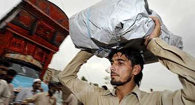 Ein Flüchtling transportiert seinen Besitz auf dem Kopf.