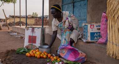 Eine Frau sitzt auf dem Boden und verkauft Gemüse.