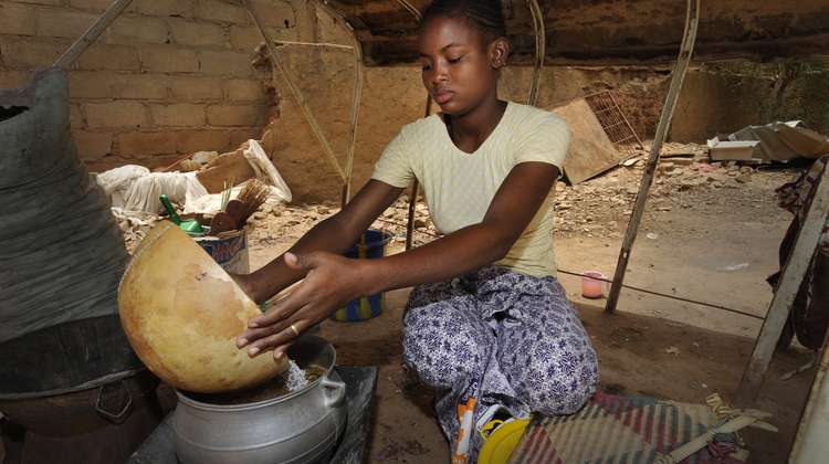 Frau schüttet Zutaten aus einem Korb in einen Kochtopf
