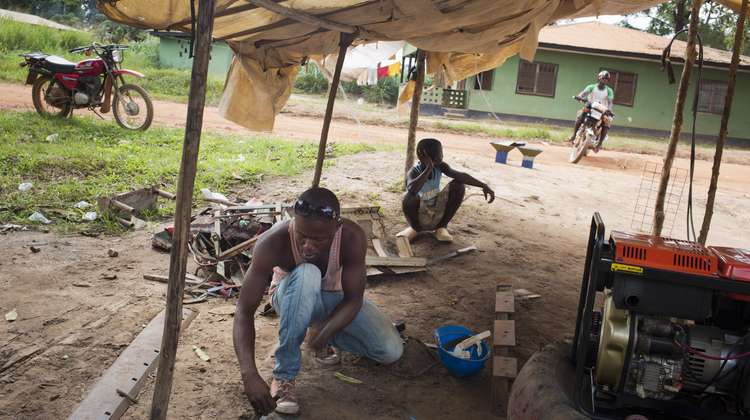 Der Metallarbeiter Papa Gaye in seiner Metallwerkstatt in Zwedru, Liberia, am 19.06.2015. Hier baut er einen Kohleofen zum Kochen. 