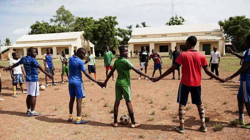 Kinder in Fußballtrikots halten sich an den Händen.