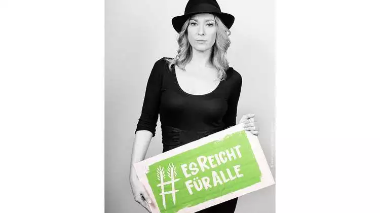 Schauspielerin Astrid Leberti hält ein Schild mit dem Welthungerhilfe-Hashtag #EsReichtFürAlle.