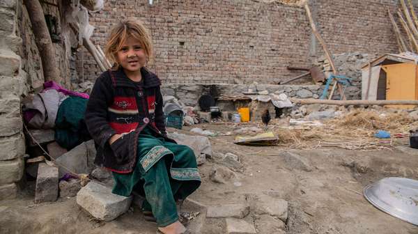 Mädchen sitzt vor Trümmern in Afghanistan