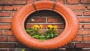 Upcycling: Ein alter Reifen hängt an einer Mauer und wird als Blumenvase genutzt, 2022.