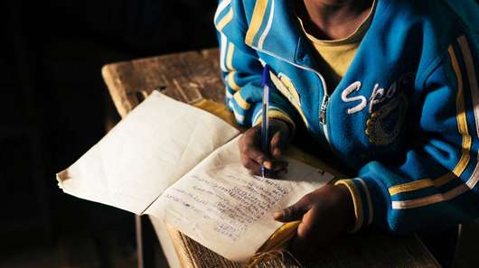 Ein Junge schreibt in ein Schulheft.