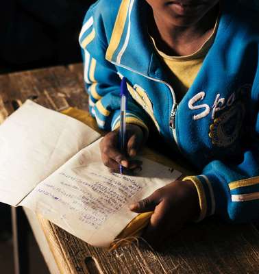 Ein Junge schreibt in ein Schulheft.