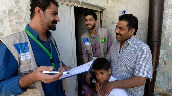 Zwei Welthungerhilfe-Männer reden mit einem Mann und einem kleinen Kind.