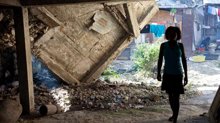Frau steht in der Ruine ihres ehemaligen Hauses in Port au Prince, Haiti.