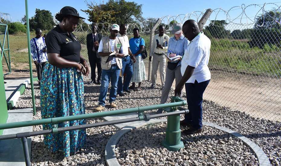 Eine Gruppe Menschen inspiziert eine Wasseranlage in Uganda