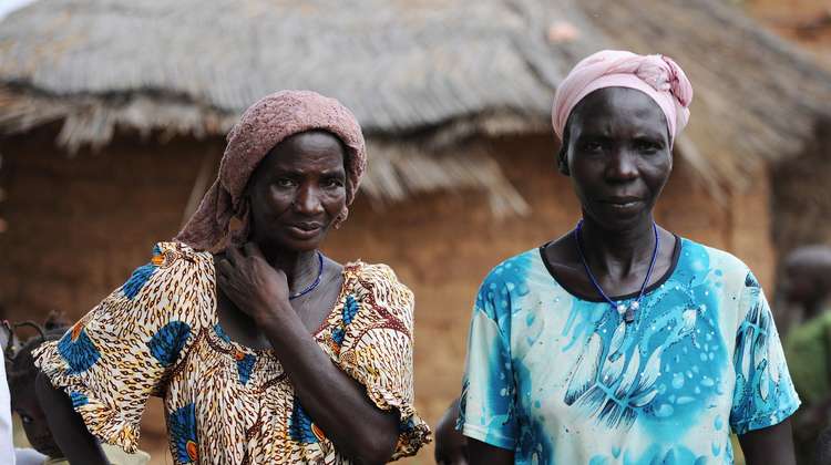 Zwei Kleinbäuerinnen in traditioneller Kleidung stehen vor einer Hütte in Burkina Faso