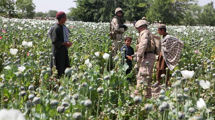 US-Soldaten grüßen Kinder in einem Mohnfeld in Afghanistan im Jahr 2011. 