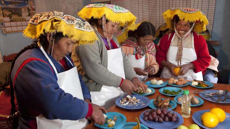 Vier Peruanerinnen stehen an einem Tisch und kochen zusammen
