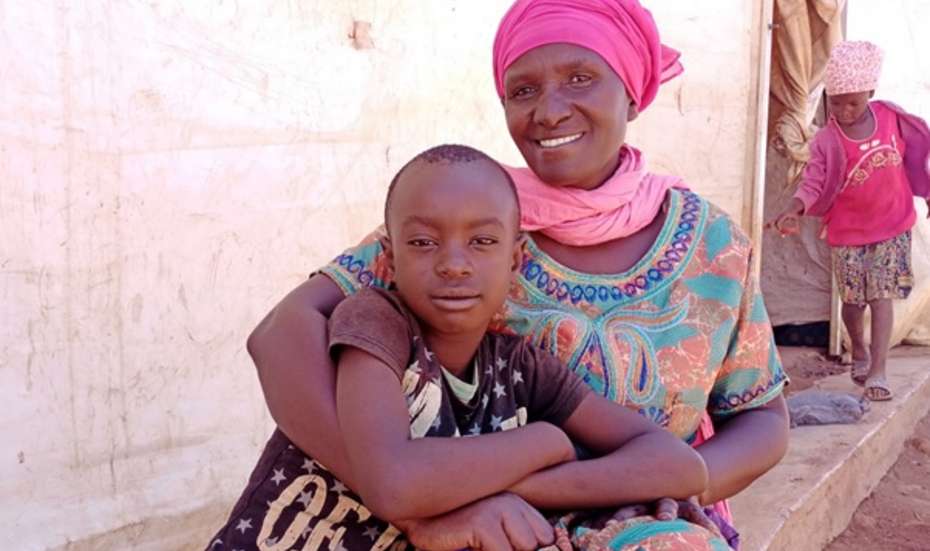 Eine Mutter sitzt auf einem Bordstein und hält ihren Sohn im Arm, Malawi 2021. 