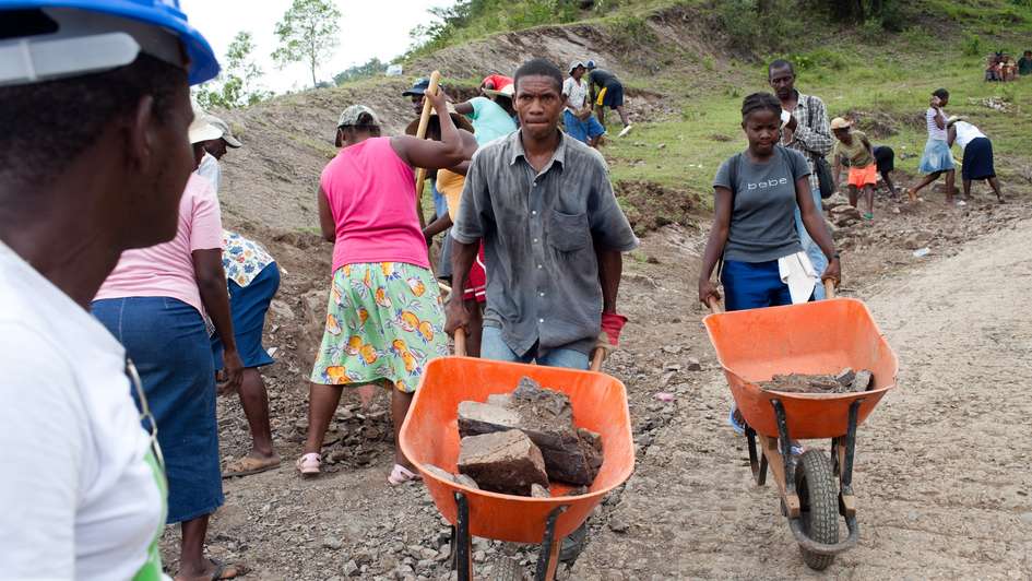 Haitianer reparieren eine zerstörte Straße.