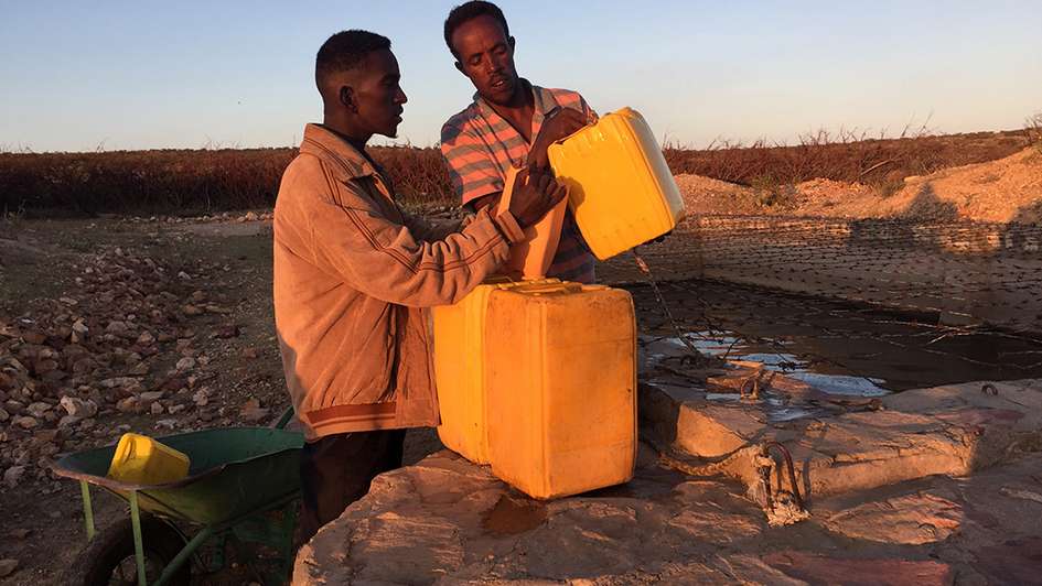 Zwei Männer befüllen Kanister mit Trinkwasser
