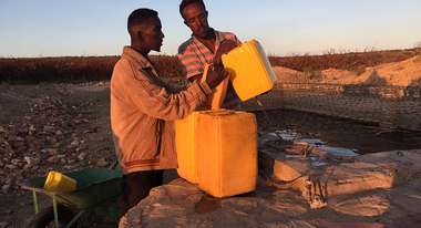 Zwei Männer befüllen Kanister mit Trinkwasser
