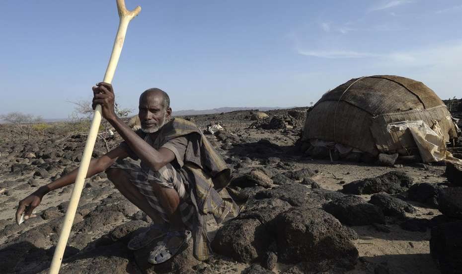 Ein Äthiopier hockt vor seinem Zelt inmitten einer kargen Umgebung