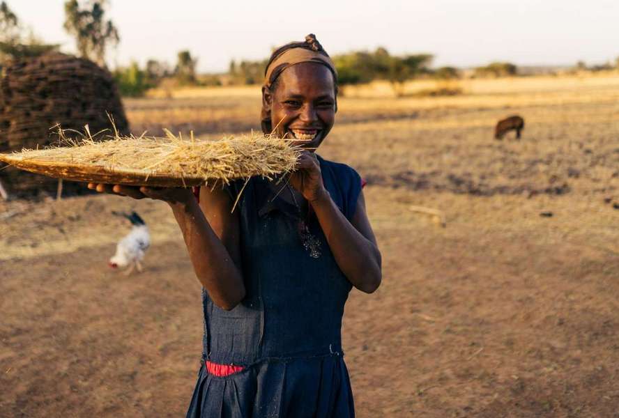 Eine Frau hält ein eine große Platte mit geerntetem Getreide in der Hand