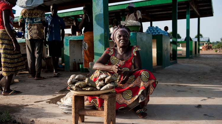 Eine Frau sitzt auf dem Boden und verkauft Gemüse.