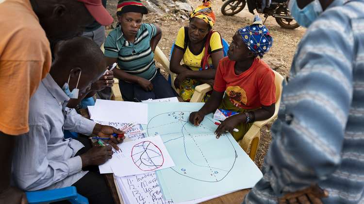 Eine Gruppe Menschen sitzt zusammen um eine Karte und berät sich, Kenia 2021.