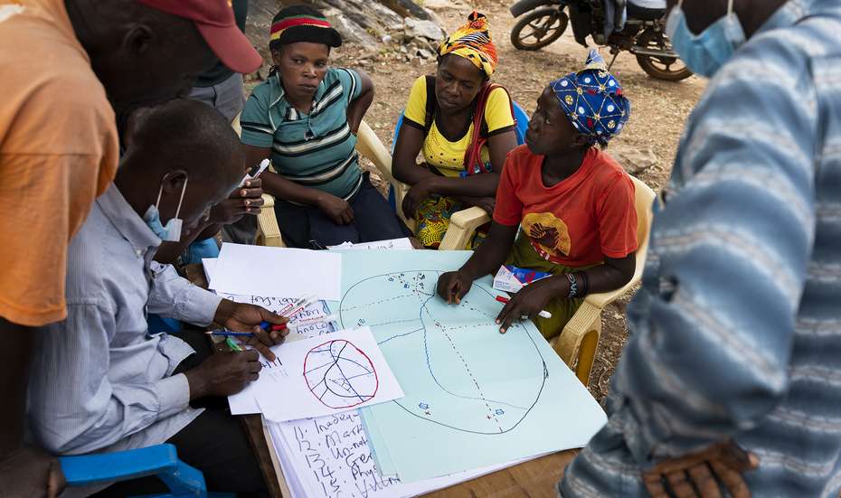 Eine Gruppe Menschen sitzt zusammen um eine Karte und berät sich, Kenia 2021.