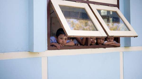 Kinder schauen durch ein halboffenes Fenster