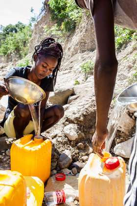 Eine Frau schöpft Wasser aus einem Fluss.