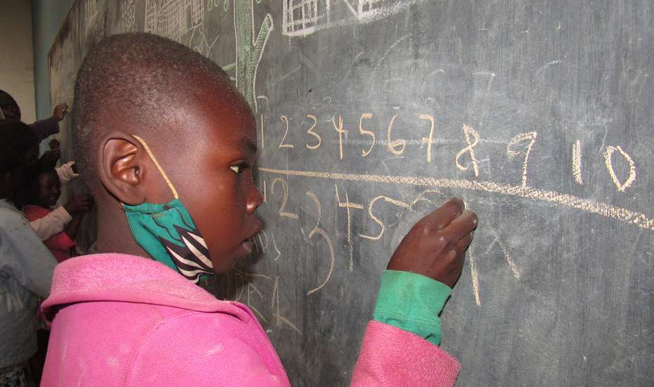 Ein Mädchen steht an der Tafel und rechnet, Malawi 2021. 