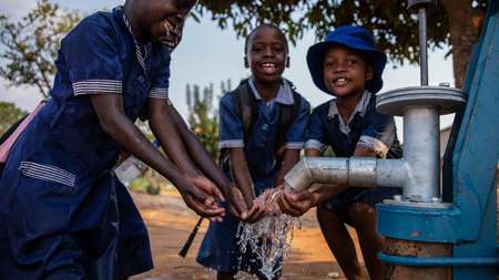 Kinder waschen sich ihre Händer an einem Brunnen, Simbabwe.