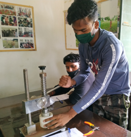 Ein junger Mann repariert eine LED-Glüchbirne, Indien 2021.