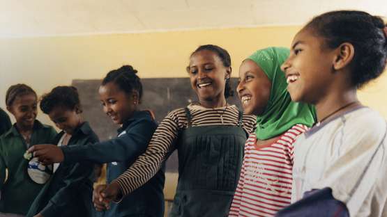 Eine Spende gegen Hunger. Bildbeschreibung: Eine Gruppe von Mädchen singen und tanzen.