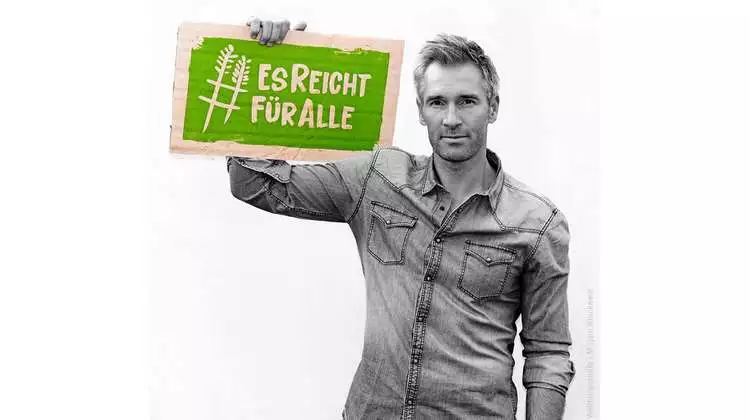 Schauspieler Ben Braun hält ein Schild mit dem Welthungerhilfe-Hashtag #EsReichtFürAlle.